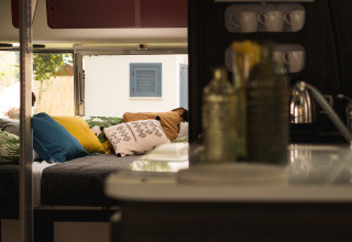 Interieur van PROCIDA Camp & Resort - Luxe airstream met kleurrijke kussens en gezellige campingsfeer.