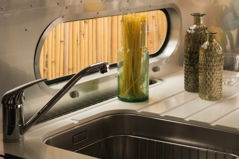 Moderne køkkenvask i en glamping airstream med stilfulde glasflasker og spaghetti på Procida Camp & Resort.