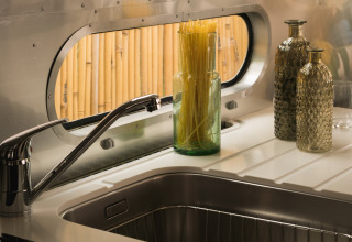 Moderne køkkenvask i en glamping airstream med stilfulde glasflasker og spaghetti på Procida Camp & Resort.