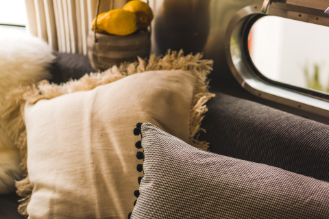 Cozy PROCIDA Camp & Resort airstream interior with soft cushions on a sofa near a large retro-style window.