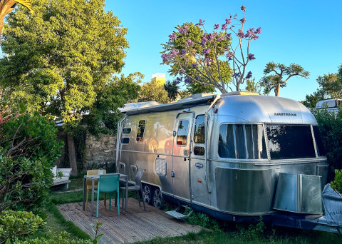 Glamping accommodation at PROCIDA Camp & Resort featuring a luxe Airstream trailer and cozy outdoor seating.