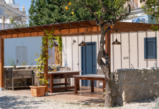 Outdoor kitchen area with wooden pergola and seating at Procida Camp & Resort - Luxe airstreams.