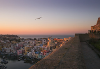 Zonsondergang met uitzicht op kleurrijke huizen bij PROCIDA Camp & Resort - Luxe airstreams in Procida.