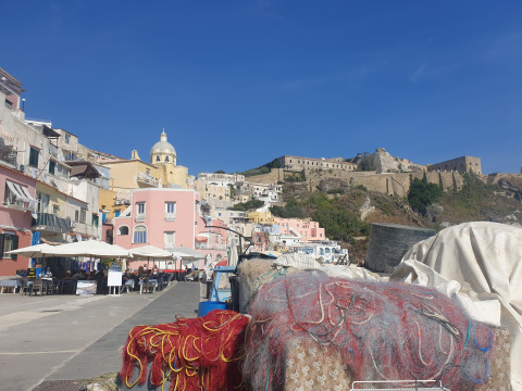 Veduta del porto di Procida vicino a PROCIDA Camp & Resort - Luxe airstreams con case colorate e cielo blu.