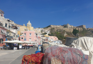 Solrig havnefront med farverige bygninger i Procida nær PROCIDA Camp & Resort - Luxe airstreams, Italien.