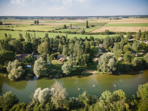 Luchtfoto van Huttopia La Plage Blanche - Glamping Franche-Comté met rivier, bomen en weilanden.