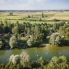 Aerial view of Huttopia La Plage Blanche - Glamping Franche-Comté with river, trees, and open fields.
