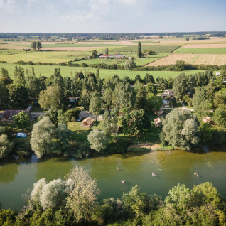 Luchtfoto van Huttopia La Plage Blanche - Glamping Franche-Comté met rivier, bomen en weilanden.