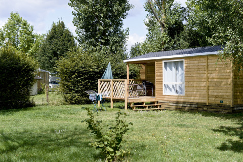 Cabina in legno presso Huttopia La Plage Blanche - Glamping Franche-Comté, immersa nel verde e negli alberi.
