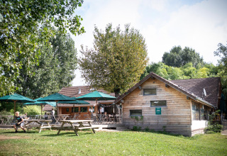 Huttopia La Plage Blanche en Franche-Comté : hébergements glamping en bois et terrasses avec parasols verts.