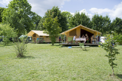 Alloggio glamping a Huttopia La Plage Blanche, Franche-Comté, con grandi tende e verde intorno.