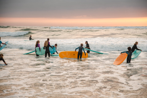 Niños con tablas de surf al atardecer en la playa cerca de las lodges Surf Tribe en Biscarrosse, Francia.
