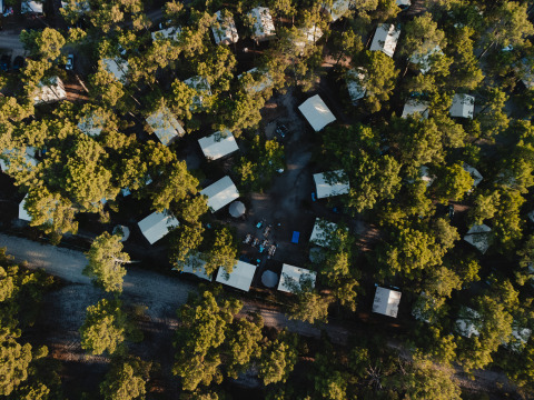 Vista aerea dei lodge glamping Surf Tribe a Biscarrosse, Francia, circondati da alberi verdi.