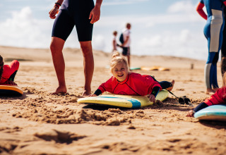 Enfants initiés au surf sur la plage de Biscarrosse avec Surf Tribe, équipés de combinaisons et planches.