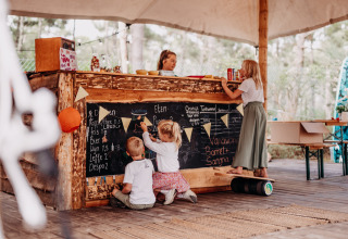 Bambini giocano presso un bar all’aperto con lavagne al Surf Tribe glamping a Biscarrosse, Francia.