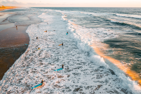 Surfers ride morning waves at Surf Tribe in Biscarrosse – Lodges in Biscarrosse, France, near the sandy beach.