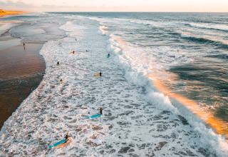 Surfeurs profitent des vagues au lever du soleil à Surf Tribe in Biscarrosse – Lodges à Biscarrosse, France.