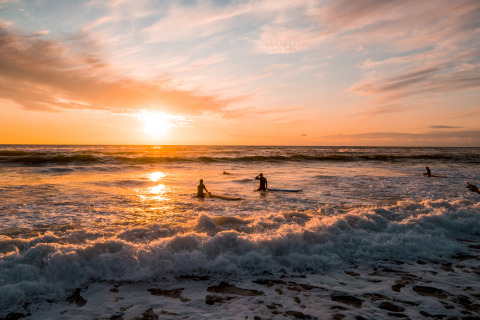 Surfers in de branding bij zonsondergang bij Surf Tribe lodges in Biscarrosse, Frankrijk voor glamping.