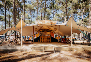 Alojamiento glamping Surf Tribe en Biscarrosse, Francia, con terraza de madera rodeada de pinos.