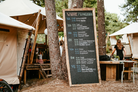 Alojamiento glamping Surf Tribe en Biscarrosse, Francia, con lodges y pizarra de actividades semanales.