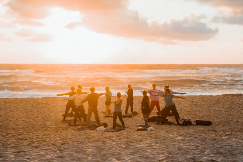 Un grupo de personas practicando yoga en la playa al atardecer junto al mar en Surf Tribe en Biscarrosse, Francia.
