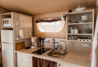 Moderne glampingkeuken met spoelbak, kookplaat, koelkast en open kast in Surf Tribe Biscarrosse, Frankrijk.