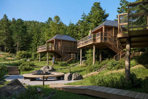 Glamping Village Kötschach - Boomhutten Karinthië : cabanes perchées et terrasses dans une forêt verdoyante autrichienne.