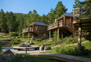 Glamping Village Kötschach - Boomhutten Karinthië: Træhytter og terrasser i den frodige østrigske natur om sommeren.