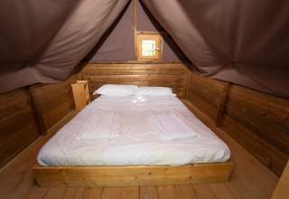 Gemütliches Glamping-Bett mit Holzverkleidung im Vallicella Glamping Resort in der Toskana, Italien.