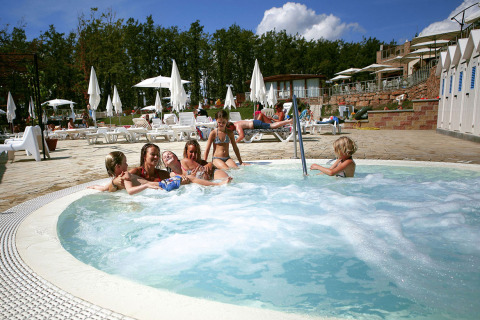 Børn leger i en boblebad ved udendørs pool på Chianti Glamping Resort – Airlodges Toscane i solrigt vejr.