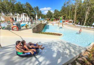 Twee personen glijden op een opblaasband richting het zwembad bij Chianti Glamping Resort in Toscane, Italië.