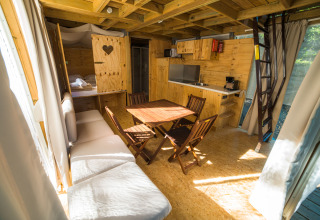 Interior of a bright glamping lodge with wood décor, kitchen, dining table, and loft ladder at Chianti Glamping Resort.