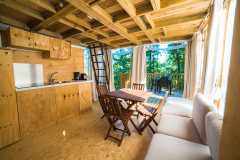 Interior de una acogedora cabaña de madera en Chianti Glamping Resort, con cocina y vistas al bosque.