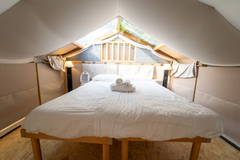 Indvendigt billede af et luksuriøst telt med stor seng og lyst interiør på Chianti Glamping Resort i Toscana.