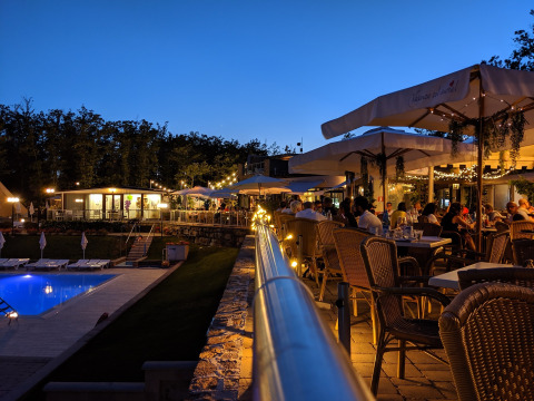 Abendliche Terrasse mit Gästen im Chianti Glamping Resort, beleuchteter Pool und entspannte Atmosphäre.