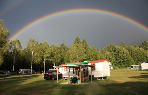 Glamping o campeggio Camping Rosental Rož - Stacarvans Karinthië con arcobaleno sopra la natura verde.