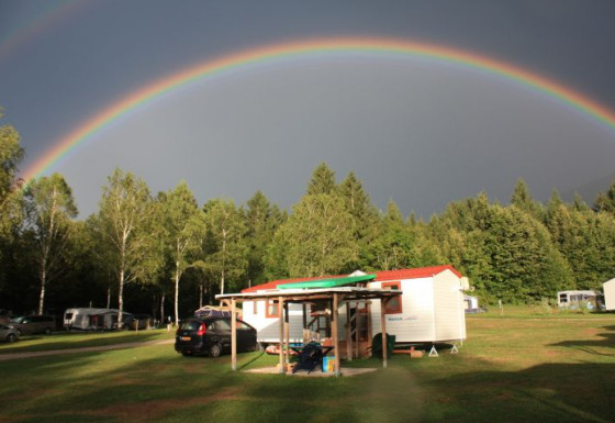 Glamping accommodatie Camping Rosental Rož - Stacarvans Karinthië met regenboog boven groene camping.