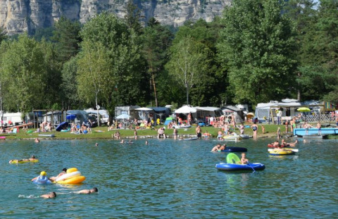Des vacanciers nagent et se détendent au Camping Rosental Rož - Stacarvans Karinthië, au bord d’un lac pittoresque.