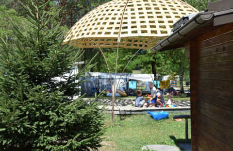 Kinderen spelen onder een gevlochten scherm bij Camping Rosental Rož - Stacarvans Karinthië in het groen.