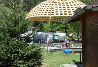 Kinderen spelen onder een gevlochten scherm bij Camping Rosental Rož - Stacarvans Karinthië in het groen.