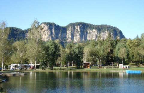 Campingplatz mit See, Bäumen und Blick auf Berge im Hintergrund, Camping Rosental Rož - Stacarvans Karinthië.