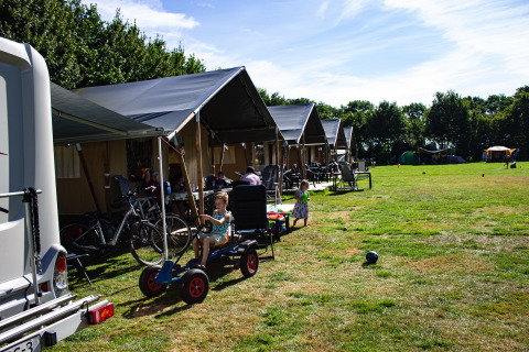 Children playing outside safari tents at Familiecamping Hendriks Wijkje - Safaritenten Drenthe campsite.