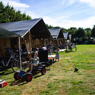 Children playing outside safari tents at Familiecamping Hendriks Wijkje - Safaritenten Drenthe campsite.