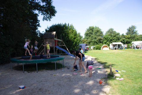 Des enfants jouent sur un trampoline et une aire de jeux au Familiecamping Hendriks Wijkje - Safaritenten Drenthe.