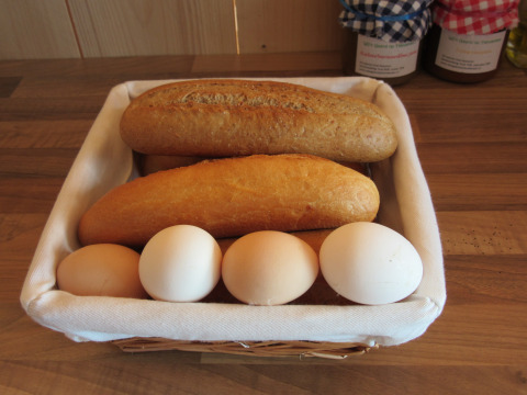 Cestino con due pani e cinque uova su un tavolo di legno, colazione a Familiecamping Hendriks Wijkje.