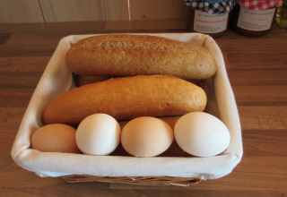 Cestino con due pani e cinque uova su un tavolo di legno, colazione a Familiecamping Hendriks Wijkje.