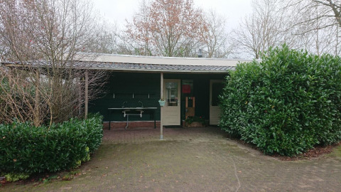 Outdoor facilities at Familiecamping Hendriks Wijkje - Safaritenten Drenthe, surrounded by shrubs and trees.