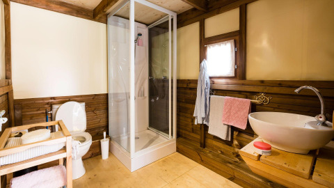 Modernes Badezimmer im Lago Idro Glamping Boutique mit Dusche, WC, Waschbecken und Holzdekor.