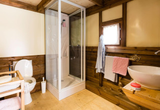Moderne badkamer bij Lago Idro Glamping Boutique met douche, toilet, wastafel en houten accenten.