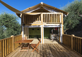 Glamping accommodation at Vacanze col Cuore: Lago Idro Glamping Boutique, wooden terrace, surrounded by trees in Italy.